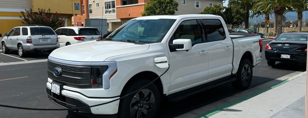 A white electronic truck charging in a parking lot