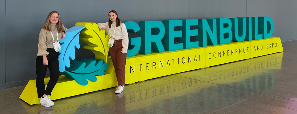 Two women standing in front of a Green Build, International Conference and Expo sign